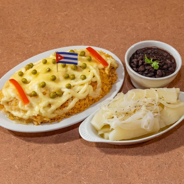 Cuban Diner's Arroz con Pollo with a Cuban flag, black beans, and yuca with onions.