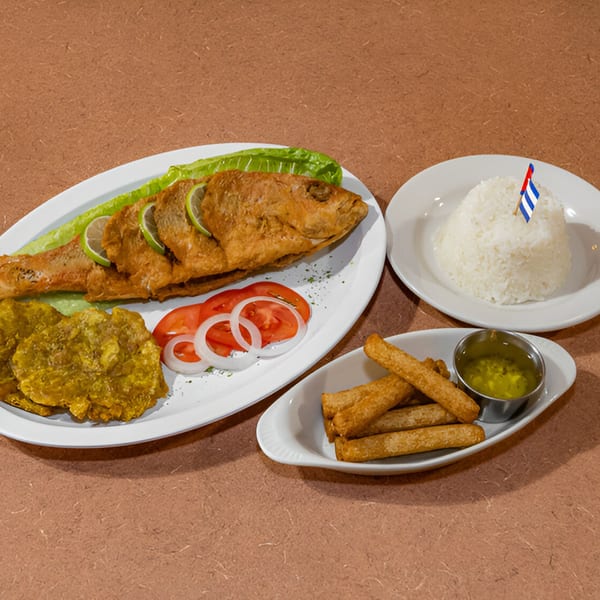 A Cuban fried whole fish with lime, lettuce, plantains, tomatoes, onions, rice, and yucca fries.